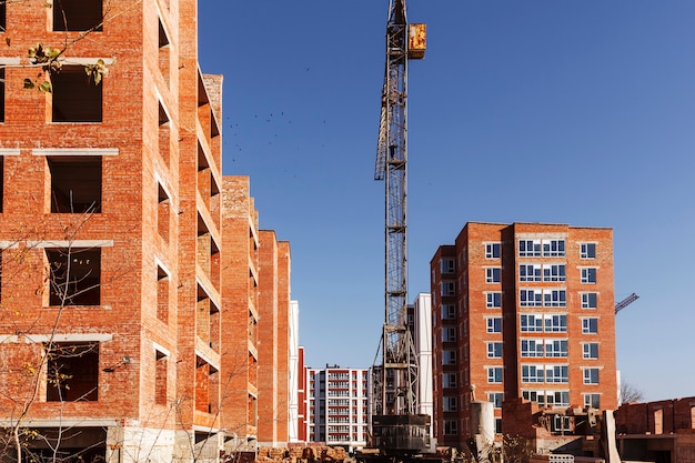 Grúa torre entre edificios de gran altura de ladrillo sobre un fondo de cielo