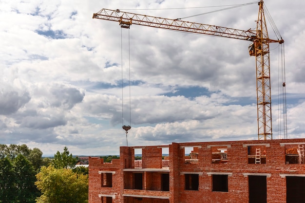 Grúa torre trabaja en sitio de construcción sobre fondo de cielo nublado