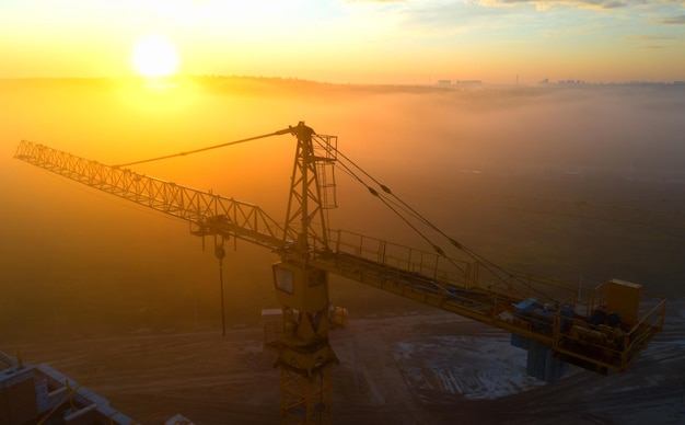 Grúas de construcción al amanecer en la niebla de la mañana.