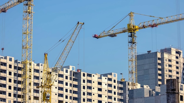 Grúas de construcción amarillas y edificios sobre fondo de cielo azul highrise skyscrappers bajo constr