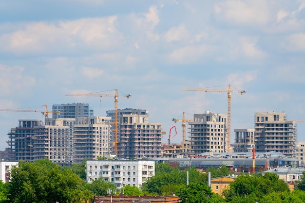 Grúas de construcción cerca de la fachada de una casa en construcción industria de la construcción moderna Venta y alquiler de bienes inmuebles