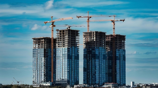 Grúas de construcción y edificios de gran altura en construcción contra el cielo azul