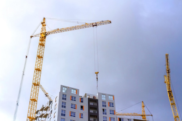 Grúas y construcción de edificios con el telón de fondo de un cielo nublado