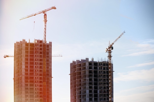 Grúas de construcción y edificios sin terminar con cielo azul de fondo