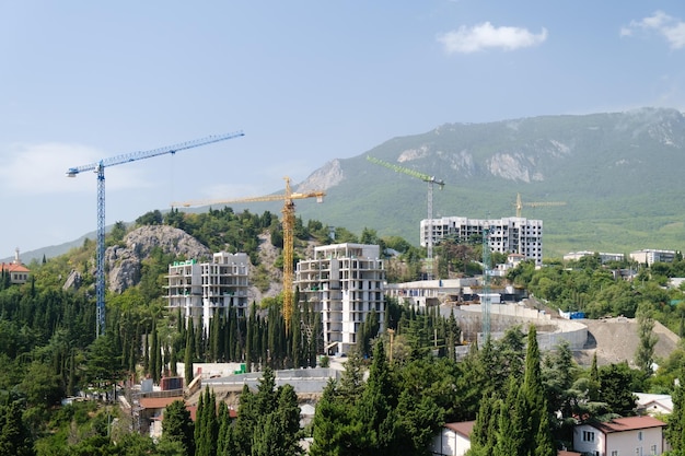 Grúas de construcción con nuevos edificios en construcción en el fondo de la montaña Construcción Edificio arquitectura desarrollo naturaleza paisaje fondo