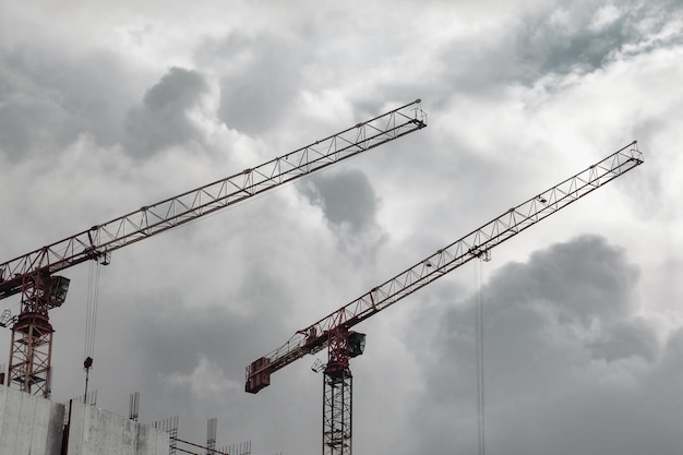 Las grúas de construcción trabajan en el sitio de creación contra el fondo del cielo azul Vista inferior de la grúa industrial Concepto de construcción de edificios de apartamentos y renovación de viviendas Espacio de copia