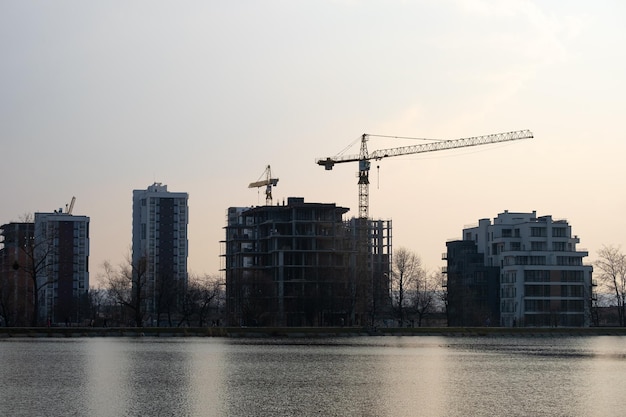 Grúas torre y altos edificios de apartamentos residenciales en construcción a orillas del lago Desarrollo inmobiliario