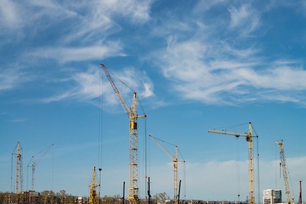 Grúas de torre grandes sobre edificios bajo construcción contra el cielo azul.