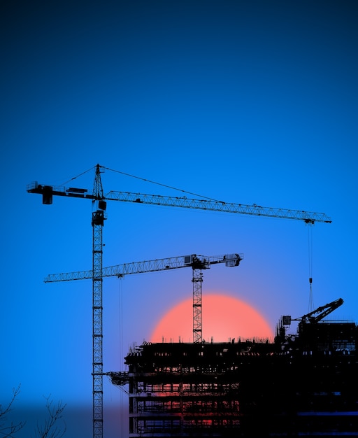 Grúas torre y silueta de edificio al amanecer