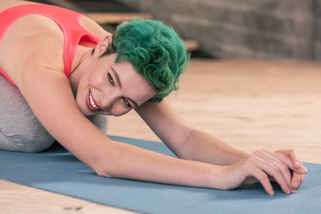 Grünäugige frau. ansprechende junge grünäugige frau, die beim stretching im fitnessstudio lächelt