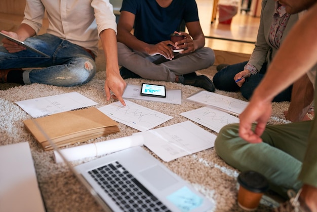 Gründliche Planung ist ein wichtiger Schritt, den Sie nicht vernachlässigen können. Nahaufnahme einer Gruppe nicht erkennbarer Geschäftsleute, die auf dem Boden in einem Büro Brainstorming betreiben