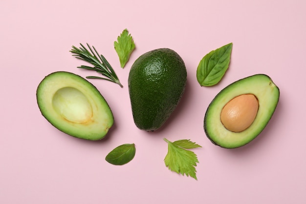 Grüne Avocado und Blätter auf rosa