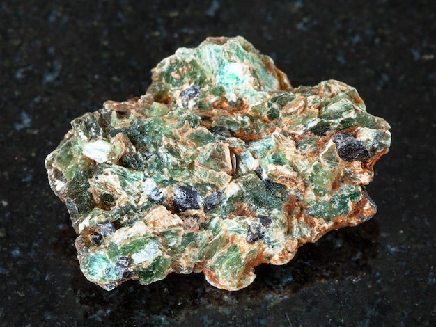 Grüne Beryllkristalle in rauem Gestein auf Schwarz