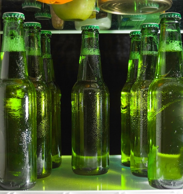 Grüne Bierflaschen auf dem Regal im Kühlschrank. Der Nebel auf dem Glas.