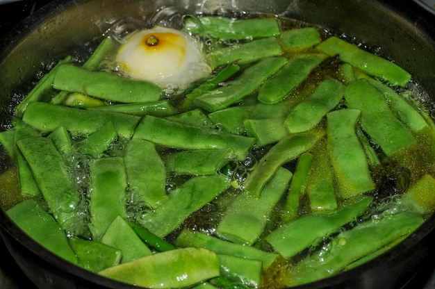 Grüne Bohnen, die in einem Topf in der Küche kochen