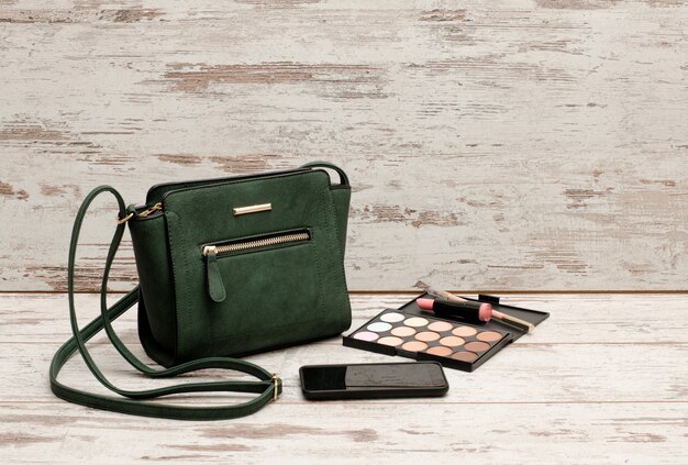 Grüne Damenhandtasche, Telefon, Lidschatten-Palette und Lippenstift