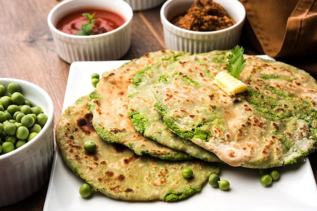 Grüne Erbsen gefülltes Fladenbrot oder Matar ka Paratha ist ein traditionelles Essen aus Nordindien. serviert mit Mangogurke, über stimmungsvollem Hintergrund, selektiver Fokus