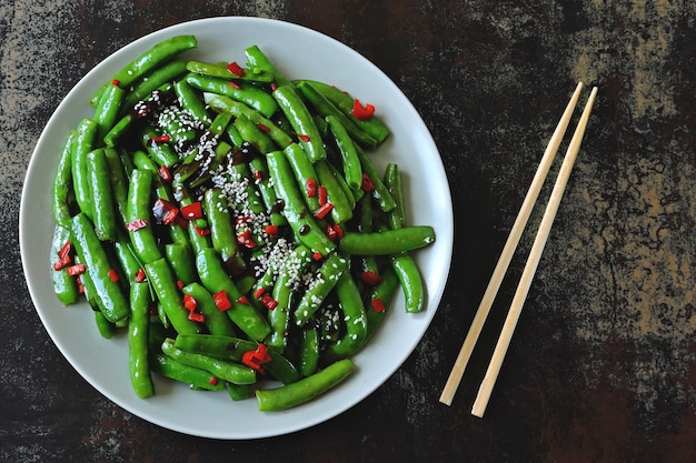 Grüne Erbsenschoten mit Chili und Sesam. Grüne Hülsen im chinesischen Stil.