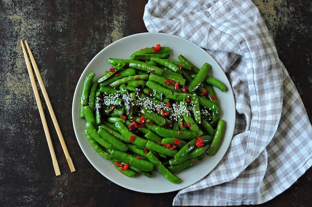 Grüne Erbsenschoten mit Chili und Sesam. Grüne Hülsen im chinesischen Stil.