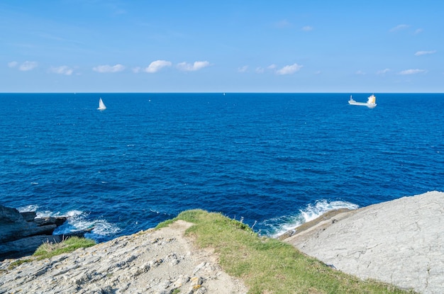 Grüne felsige Küste von Santander mit Booten im Hintergrund