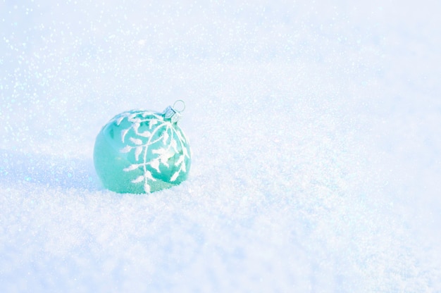 Grüne Glasweihnachtskugel auf weißem Schnee