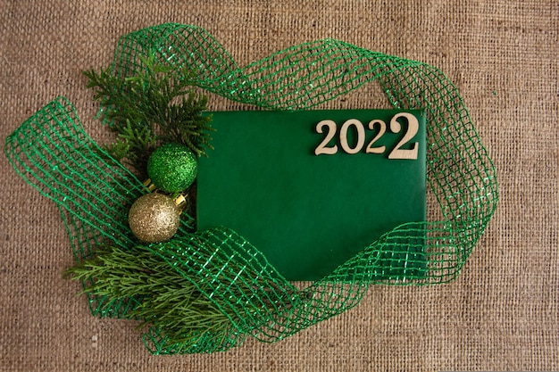 Grüne Grußkarte der neuen Jahr- und Weihnachtszusammensetzung auf stilvollem Kopienraum des Sackleinenhintergrundes