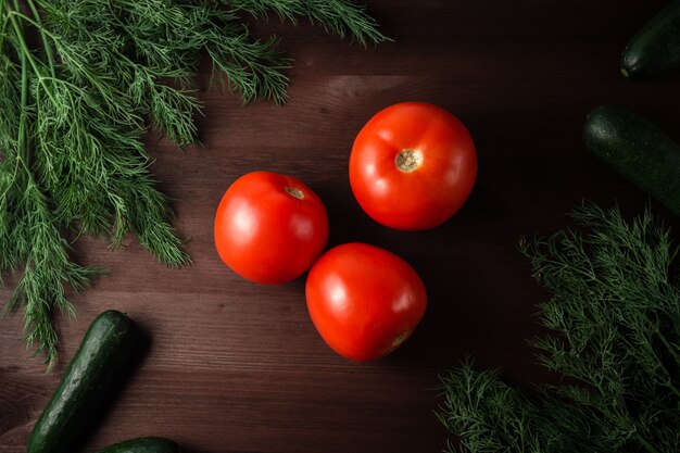 Grüne gurken, tomaten und kräuter auf einem holztisch