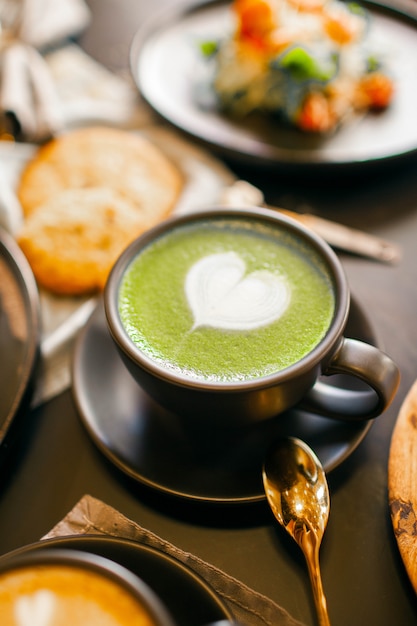 Grüne Kaffeetasse mit Herz auf Schaum