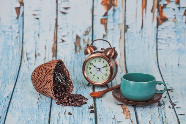 grüne Kaffeetasse und Kaffeebohnen auf altem hölzernem Hintergrund