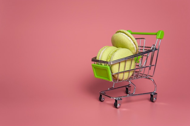 grüne Macarons in einem Wagen auf rosa Hintergrund