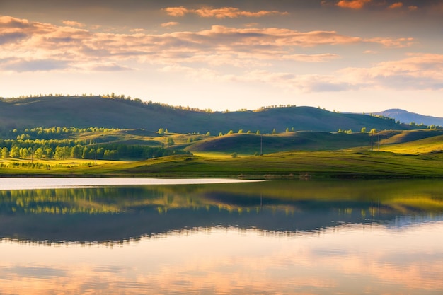 Grüne muntains bei Sonnenuntergang und ihre Reflexionen im See. Schöne Sommerlandschaft. Südural, Russland