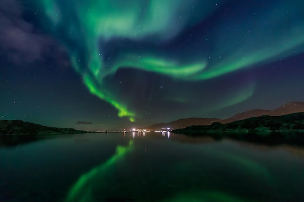 Foto grüne nordlichter, die sich im see mit bergen und der stadt im hintergrund spiegeln nuuk, grönland