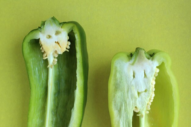 Foto grüne paprika im abschnitt mit kreativem gesicht auf gelbem hintergrund