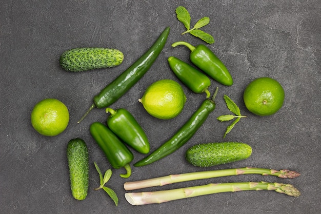 Grüne Paprika, Spargel, Gurken und Limetten auf dem Tisch. Schwarzer Hintergrund. Flach legen