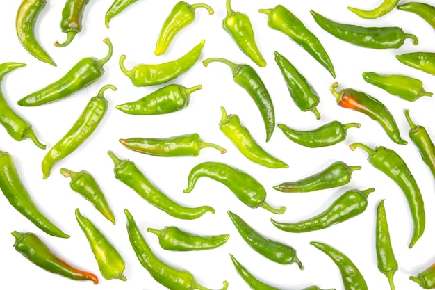 Foto grüne peperoni gleichmäßig auf weißem hintergrund verteilt. vitamingemüse für die gesundheit