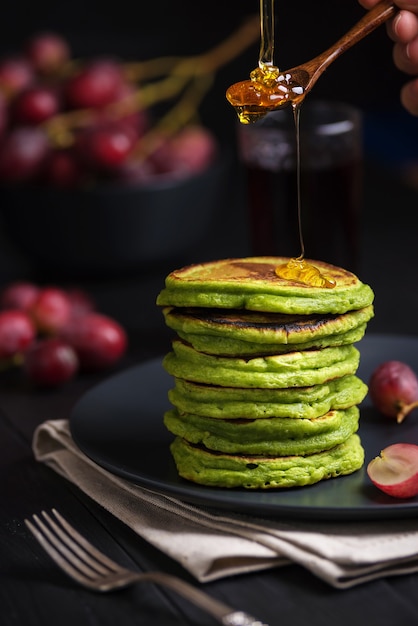 Grüne Pfannkuchen mit Matcha-Tee oder Spinat, Honig und roten Trauben