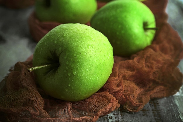 Grüne Äpfel auf Holztisch mit Stoffnahaufnahme