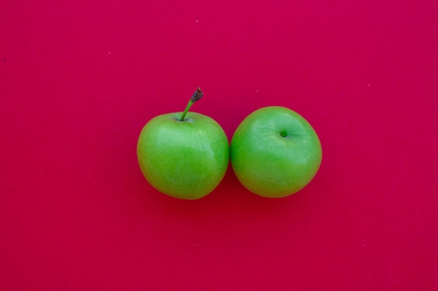 Grüne Pflaumen lokalisiert auf rotem Hintergrund. Draufsichtfoto von grünen Pflaumenfrüchten. Konzept der gesunden Ernährung.