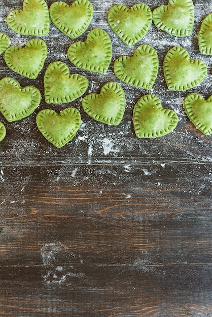 Foto grüne ravioli in herzform auf holzunterlage