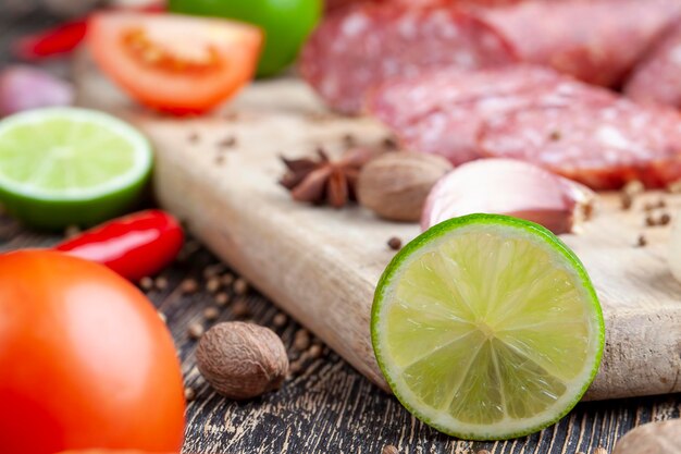 Grüne reife Limette in Scheiben geschnitten neben Fleisch und Gewürzen Kochen mit Limettenwurst mit Speck, Knoblauch und verschiedenen Gewürzen