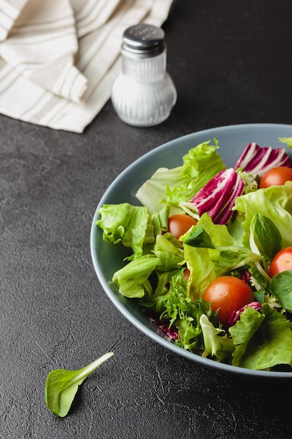 Grüne Salatblätter in Schüssel auf schwarzem Tisch