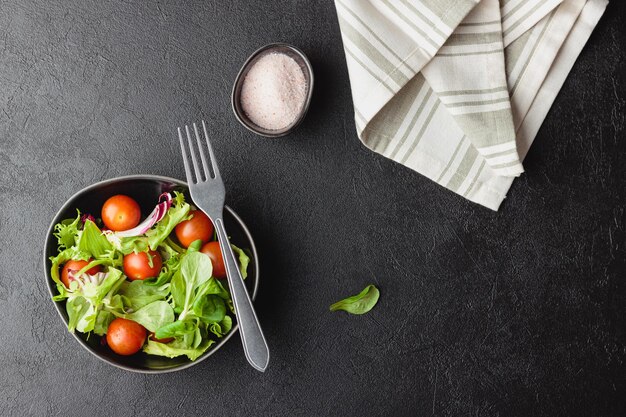 Grüne Salatblätter in Schüssel auf schwarzem Tisch