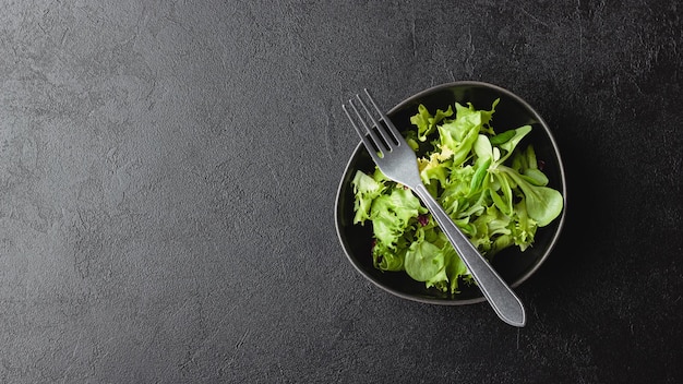 Grüne Salatblätter in Schüssel auf schwarzem Tisch