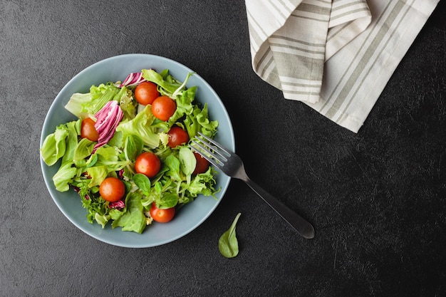 Grüne Salatblätter in Schüssel auf schwarzem Tisch