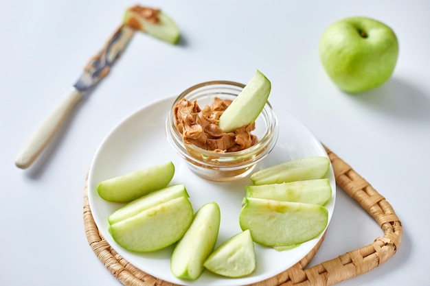 Grüne Scheiben Äpfel mit Erdnussbutter auf weißem Hintergrund gesunder Snack