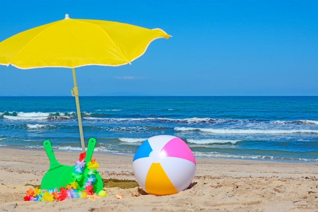 Grüne Schläger und Wasserball unter einem gelben Sonnenschirm