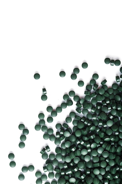 Grüne Tabletten aus natürlicher Bio-Spirulina auf weißem Hintergrund mit freiem Platz