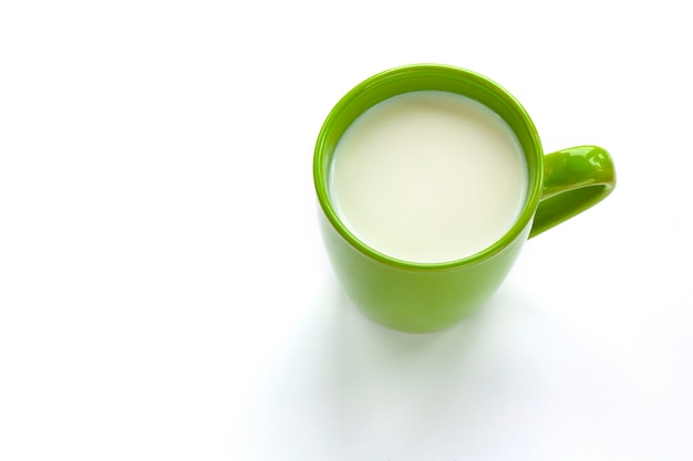 Grüne Tasse mit Milch wird auf einem Weiß isoliert