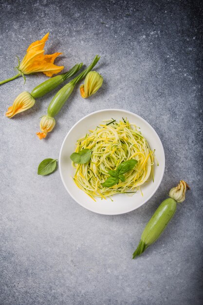 Grüne Zoodles oder Zucchinispaghetti auf Teller über grau