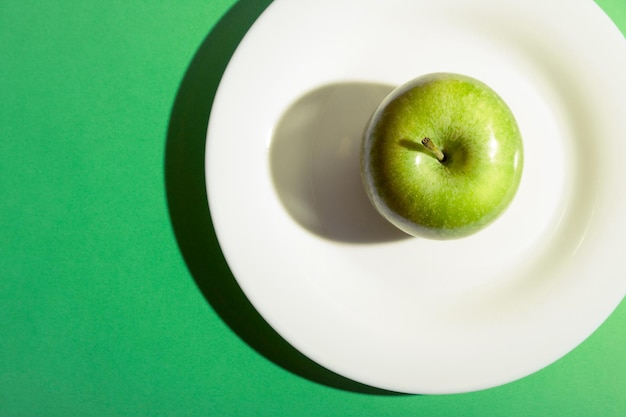 Grüner Apfel auf einem weißen Teller Granny Smith grüner Appel mit dunklem Schatten
